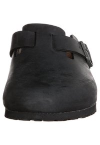 Schwarze Lederclogs mit verstellbarem Riemen, abgerundeter Zehenpartie und flacher Gummisohle. Glatte Textur mit minimalen dekorativen Elementen.