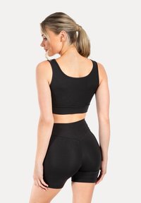 Zwarte sportieve crop top en high-waisted shorts, met een gladde textuur en een getailleerd ontwerp, brede schouderbanden en een naadloze achterkant.