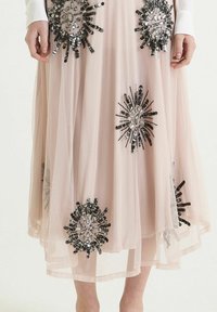 Jupe en tulle rose ornée de grandes et complexes embellissements noirs et argentés évoquant des motifs floraux, avec une silhouette fluide et superposée.