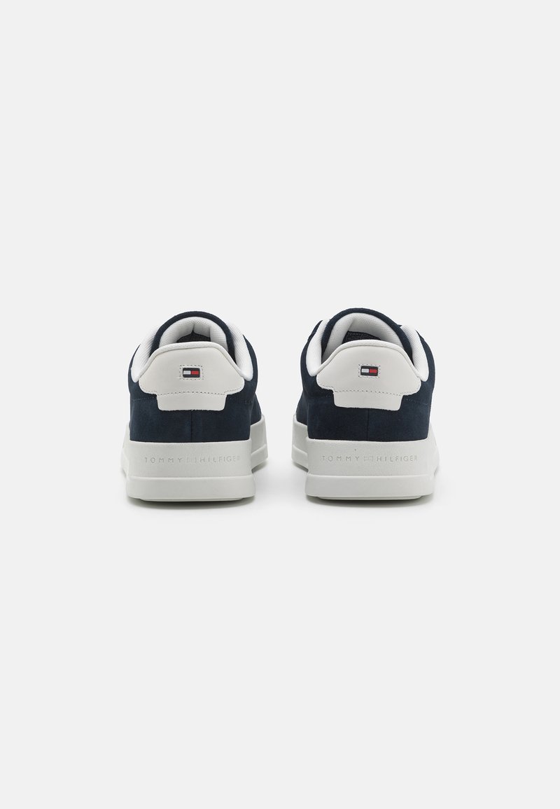 Baskets en daim bleu marine avec des accents blancs, semelles en caoutchouc plates et branding en relief sur le talon. Comprend un col rembourré pour le confort.