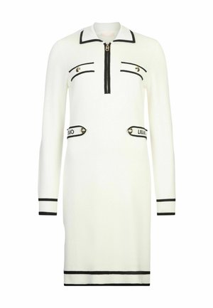 Abito di maglia bianco con colletto, chiusura lampo frontale e dettagli neri. Presenta due tasche decorative con loghi e polsini e orlo a costine.