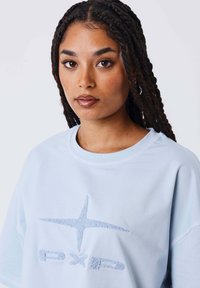 Lichtblauwe katoenen T-shirt met ronde hals, met een gewoven wit logo en een effen design; ontspannen pasvorm met korte mouwen.