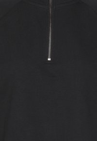 Svart zip-up sweatshirts med hög krage, med en silvrig dragkedja och mjukt, något texturerat tyg, designad med raglanärmar.