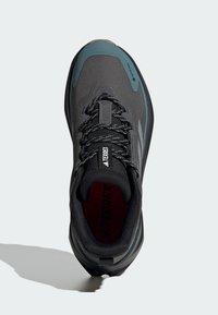 Czarne buty turystyczne z teksturowanym wierzchem, szarymi akcentami, wzmocnionym noskiem i odblaskowymi sznurowadłami. Widoczna metka GORE-TEX z boku.