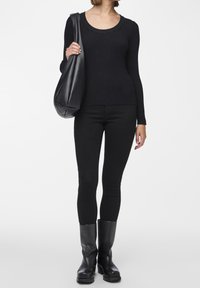 Black ribbed long-sleeve top, paired with black fitted pants and knee-high black leather boots. The model carries a black shoulder bag.