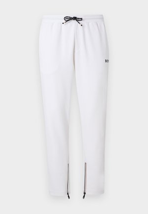 Λευκό slim-fit παντελόνι φόρμας με ασπρόμαυρο κορδόνι, πλαϊνές τσέπες, μικρό λογότυπο στο πλάι και φερμουάρ στους αστραγάλους με τρίχρωμη επένδυση.