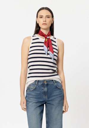 Ärmelloses gestreiftes Stricktop in Beige und Navy, kombiniert mit blauen Jeans mit hoher Taille. Ein rotes Halstuch sorgt für einen Kontrast am Hals.