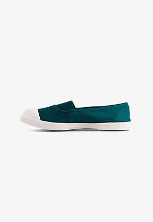 Chaussure en toile vert foncé à enfiler avec embout en caoutchouc blanc et semelle blanche texturée, présentée de profil sur fond blanc.
