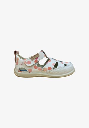 Sandalia blanca de niño con estampado de lunares rosas, correa ajustable de velcro y diseño de punta cerrada sobre una suela beige.