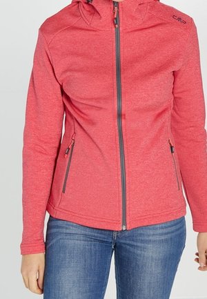 Czerwona kurtka z kapturem na zamek błyskawiczny, z bocznymi kieszeniami na zamek, noszona z niebieskimi dżinsami, widoczna od ramion do bioder.