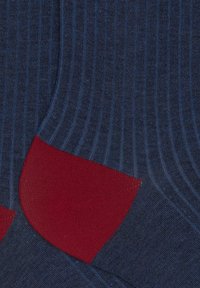 Calzini blu navy a coste con dettagli rossi pieni sul tallone e sulla punta, realizzati in materiale morbido, con una texture uniforme su tutta la superficie.