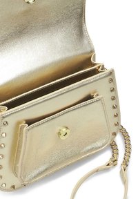 Bolso de cuero dorado con acabado metálico, que presenta acentos de tachuelas y una solapa frontal. Incluye una correa de cadena desmontable y un interior espacioso.