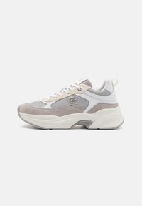 Zapatillas que combinan cuero gris y blanco con un superpuesto de ante texturizado, suela gruesa y un acento metálico del logo en el costado.