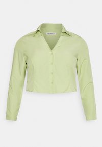 Blusa de mangas longas encurtada em tecido verde claro. Apresenta um colarinho, fecho de botão à frente e uma textura suave.