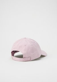 Pink cotton baseball cap with a curved brim, adjustable back strap, and ventilation holes for breathability. Simple design and smooth texture.