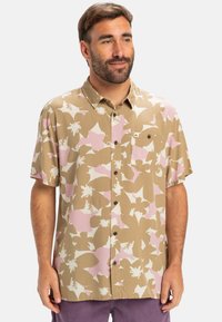 Kurzarmhemd in Beige mit rosa-weißer Blumenmusterung. Verfügt über ein Button-Down-Design und eine einzelne Brusttasche mit Logo.