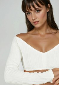 Weißes gestricktes Crop-Top mit schulterfreiem Design, V-Ausschnitt und strukturiertem Rautenmuster an den Ärmeln.