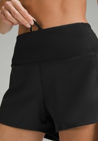 Pantaloni sportivi neri caratterizzati da una fascia elastica larga in vita e una piccola striscia sul retro. Il materiale sembra liscio ed elasticizzato.