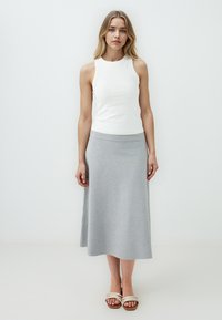 Witte mouwloze top met een ronde halslijn, gecombineerd met een lichtgrijze enkellange rok. De rok heeft een gladde textuur en een elastische tailleband.