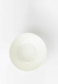White ceramic bowl with a smooth, glossy finish and a thin colored rim. Round shape and wide opening, suitable for serving or mixing.