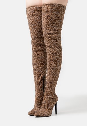 Botas por encima de la rodilla con estampado de leopardo en tonos marrón y negro, tela lisa, punta afilada y altos tacones de aguja. Detalle de cremallera lateral.