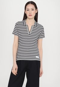 Ribaga polo-särk tumesinises ja valges triibulis graafikas, millel on krae ja lühikesed varrukad. Valmistatud ribakanga materjalist, millel on V-kaelus ja külglabel.