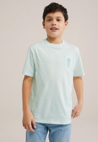 Gai mišu zaļš kokvilnas t-krekls ar kabatu kreisajā pusē, kurā ir bāka. Īsas piedurknes un klasiskas apļveida kakla dizains.