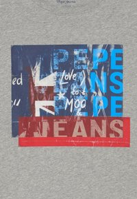 Szara bawełniana koszulka z graficznym wzorem w niebieskie, czerwone i białe elementy, w tym tekst oraz wzór flagi brytyjskiej.