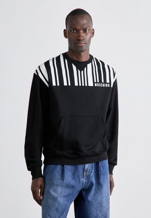 Schwarzer Pullover mit vertikalen weißen Streifen auf den Schultern, einer Vordertasche und dem weißen Moschino-Logo, mit einem legeren Schnitt.
