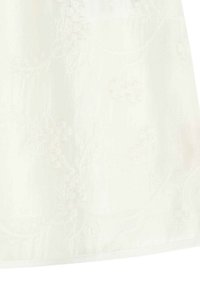 Tissu blanc brodé avec un motif floral aux détails délicats et une finition lisse et texturée. Brillance subtile du matériau.