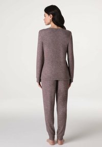 Completo loungewear a due pezzi in un colore mauve tenue, realizzato in morbido tessuto testurizzato; presenta maniche lunghe e pantaloni con polsini.