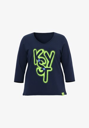 Chemise manches longues bleu marine avec col en V et texte style graffiti jaune néon "KYST" sur le devant, ainsi qu'une petite étiquette jaune à l'ourlet.