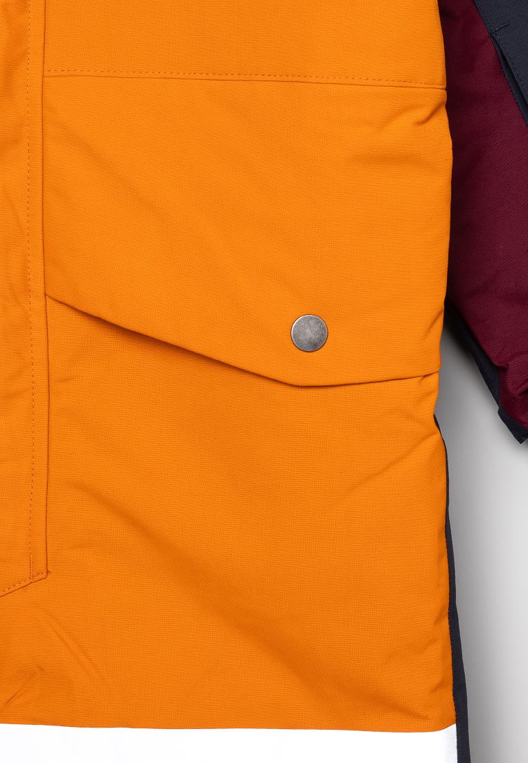 Orange tygjacka med en texturerad finish, utrustad med en knäppt ficklock, kontrasterande mörkröda och blå detaljer samt ett vitt rand upptill.
