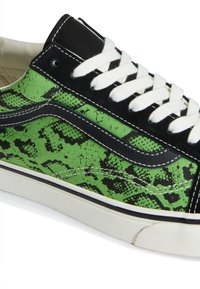 Baskets basses avec motif abstrait vert et noir, bordure en daim noir, lacets blancs et semelle en caoutchouc blanche avec détail de bande noire.