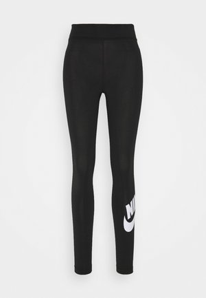 Zwarte leggings van soepel, rekbaar materiaal hebben een hoge tailleband en een groot wit Nike-logo op het linkeronderbeen.