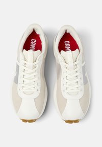 Vita och grå sportskor med en texturerad meshovandel, platt snörning och en röd innersula, med en traditionell silhuett och gummisula.