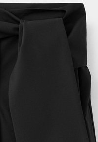 Tissu noir plié en une large ceinture ou un détail de nœud enveloppé sur un vêtement, avec une texture lisse et des bords nets.