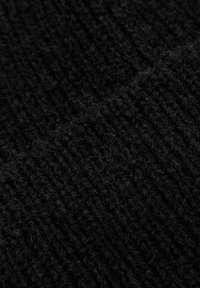 Tessuto di maglia nero, con texture che mostra un primo piano di una superficie morbida e lanosa, con un motivo rigato che evidenzia la sua densità e calore.