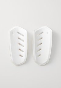 Hvite beskyttende skoinnlegg med en teksturert overflate, med spalter for ventilasjon, formet for identifikasjon av venstre og høyre fot.