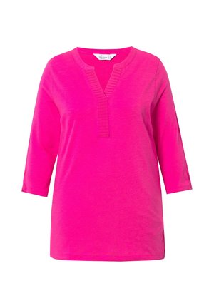 Tunic fucsia con scollo a V e dettagli a coste, caratterizzata da maniche a tre quarti e una consistenza morbida e leggera.