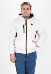 Biała pikowana kurtka z kapturem, z czarnym zamkiem błyskawicznym, żółtymi i pomarańczowymi akcentami oraz logo na piersi. Czarne boczne panele.