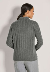 Grauer, strukturierter Pullover mit hohem Kragen und geripptem Fischgrätmuster. Enganliegende Ärmel und leicht auslaufender Saum.