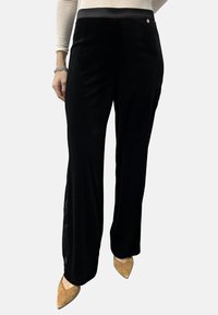 Sorte wide-leg bukser lavet af blødt materiale, med en glat talje og subtile sideaccentuer. Sammen med spidse beige sko.