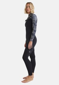 Black wetsuit with a floral-patterned long sleeve, fitted design, textured sections at the knees, and minimal branding at the ankle.
