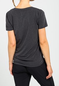 T-shirt gris à manches courtes en tissu doux. Présente une coupe décontractée avec un col arrondi et un léger drapé à l'arrière.