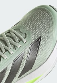Chaussure de course vert clair avec des bandes noires, tige en mesh et lacets texturés, vue en angle latéral supérieur.