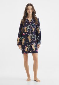 Pigiama da notte blu scuro con una vivace stampa di tigri tra foglie tropicali, accentuato da dettagli rosa e stelle. Maniche lunghe, design con bottoni.