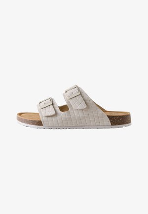 Beige sandaal met open teen, twee verstelbare gespsluitingen en een gevoerde kurken zool met witte profielzool.