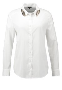 Chemise blanche à manches longues avec boutons, broderie décorative en feuilles noires et dorées sur les deux pointes du col.