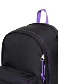 Mochila negra con detalles en púrpura, con una tela texturizada, una asa superior y un bolsillo frontal con cremallera púrpura y detalles de costura.
